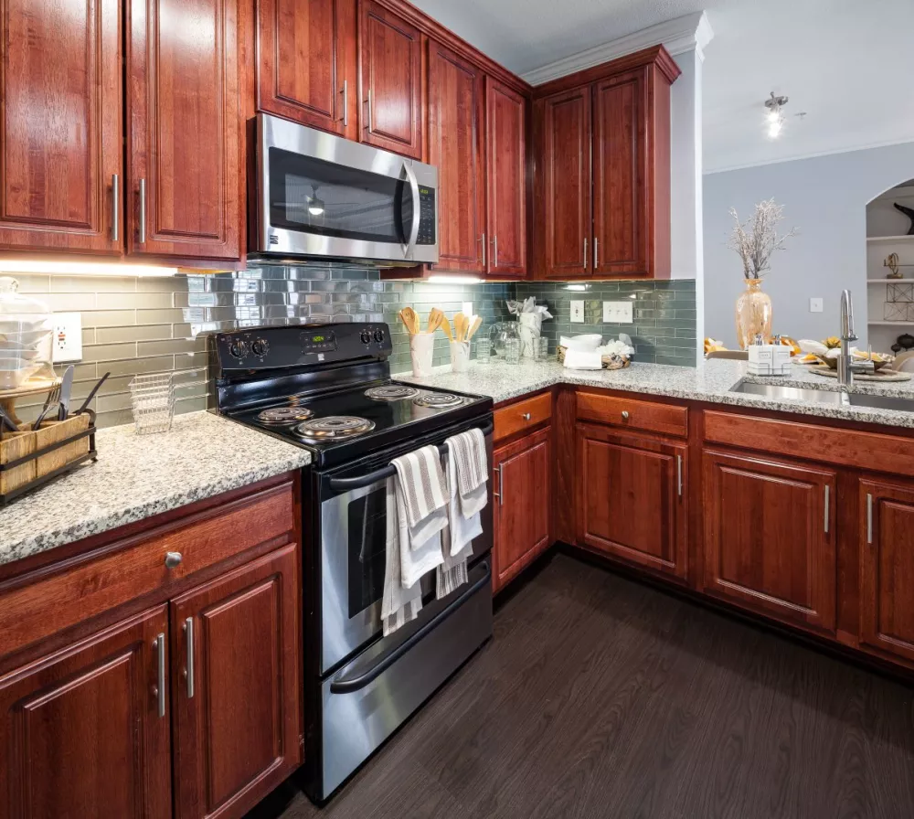 Modern kitchen with dark wood cabinets, granite counters, stainless steel appliances, and a glass tile backsplash.