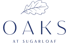 The Oaks at Sugarloaf logo, featuring a blue oak leaf design.
