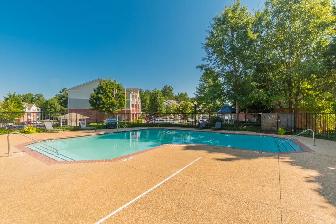 Expansive pool and sun deck surrounded by apartment buildings and trees 